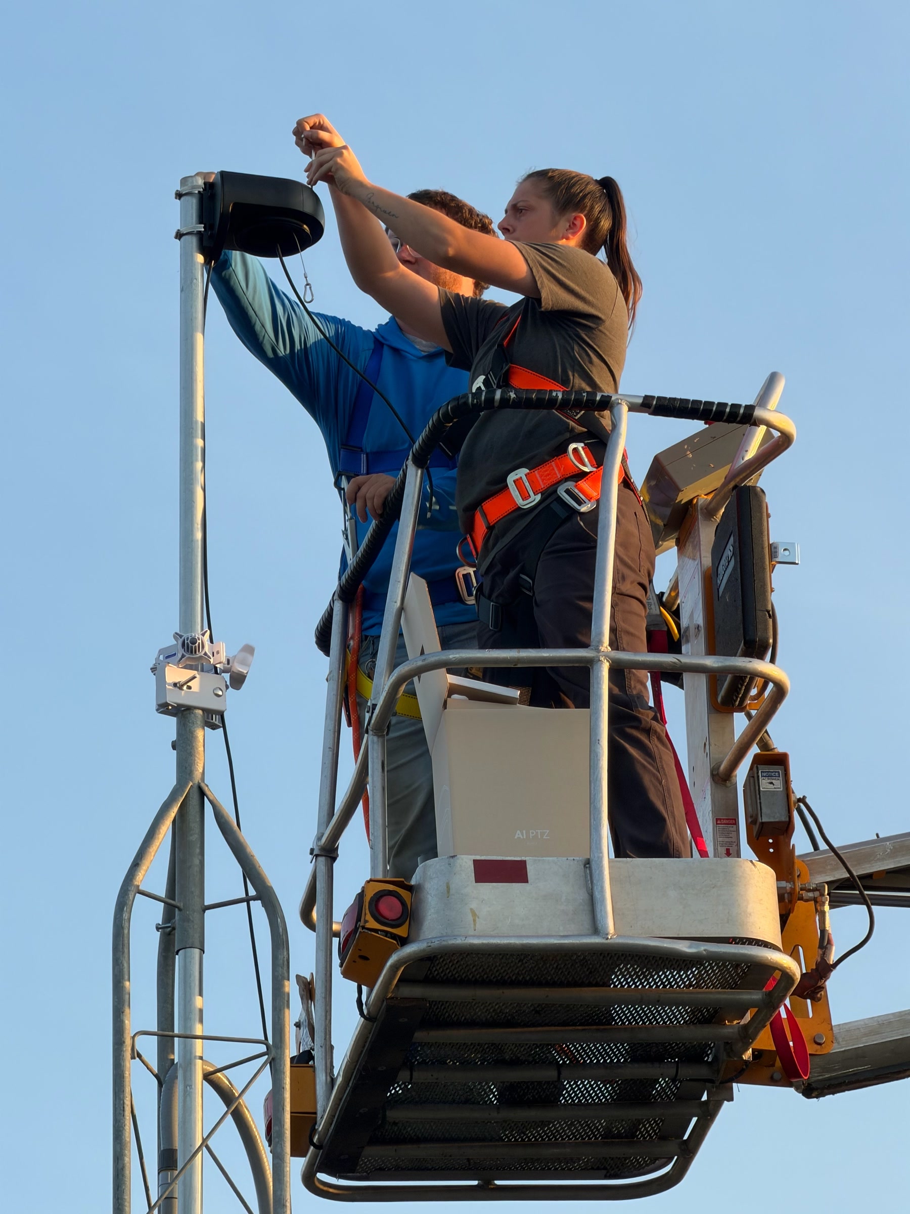 Crew in a lift mounting an AI PTZ camera on a steel pole