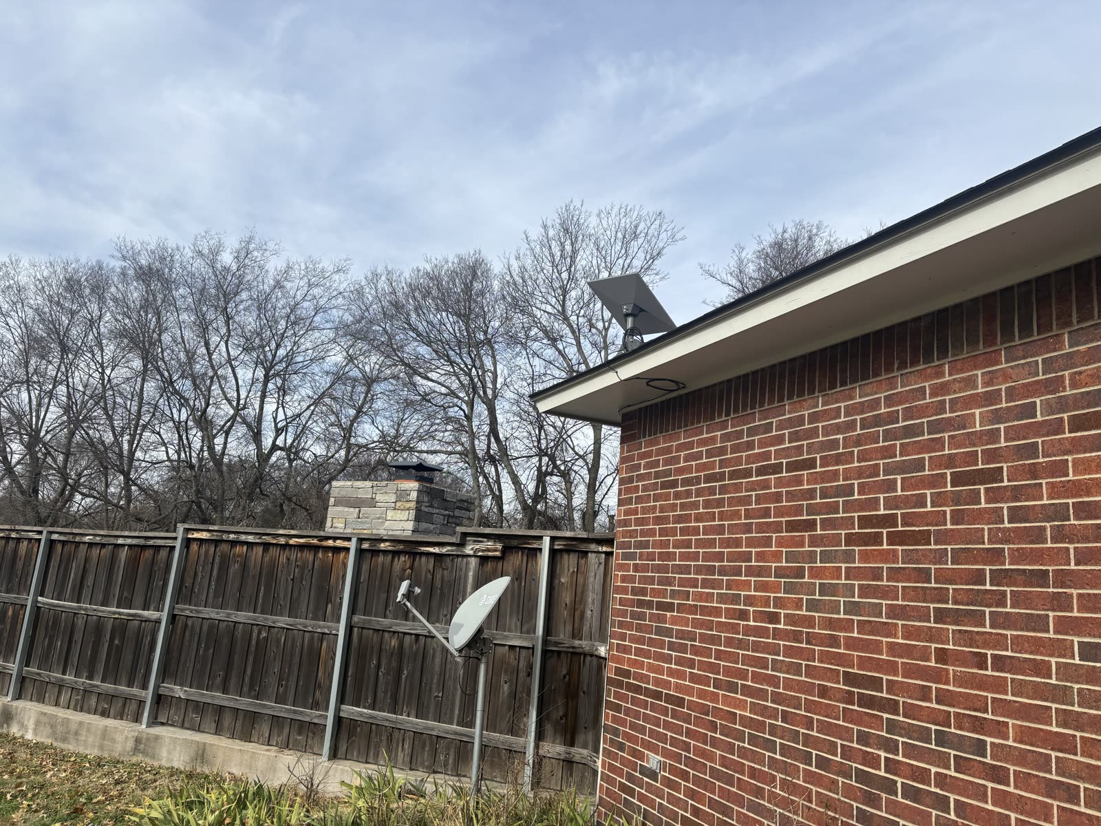 Starlink dish mounted on the roof edge of a brick house in Claremore
